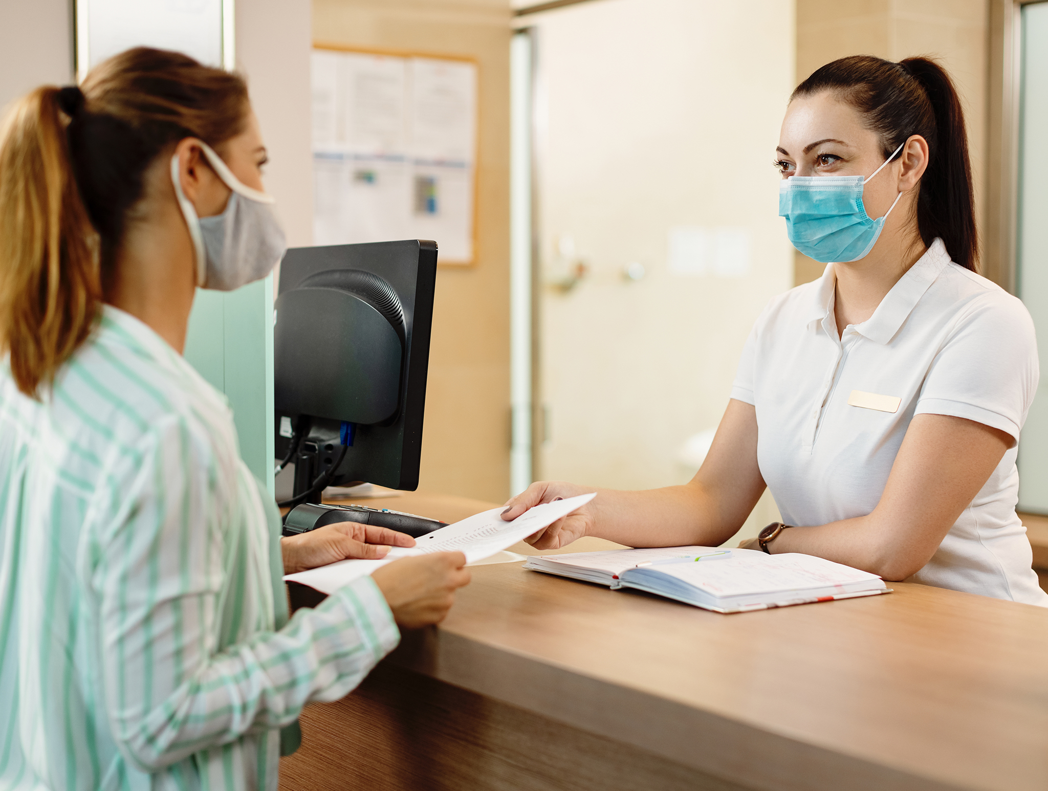 Coronis Health Medical Billing Receptionist talking to patient both wearing masks