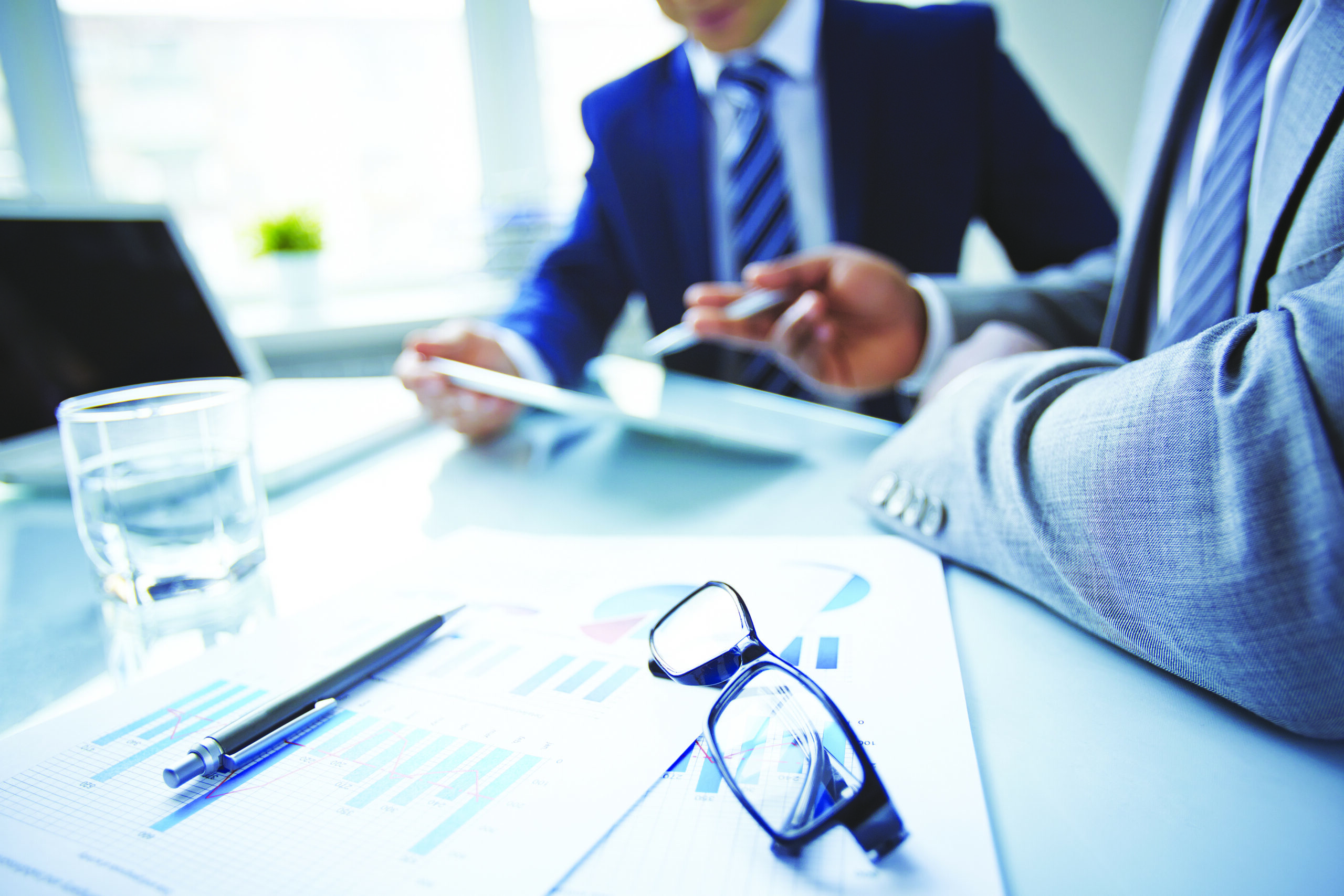 men in suites discussing work at a desk coronis health