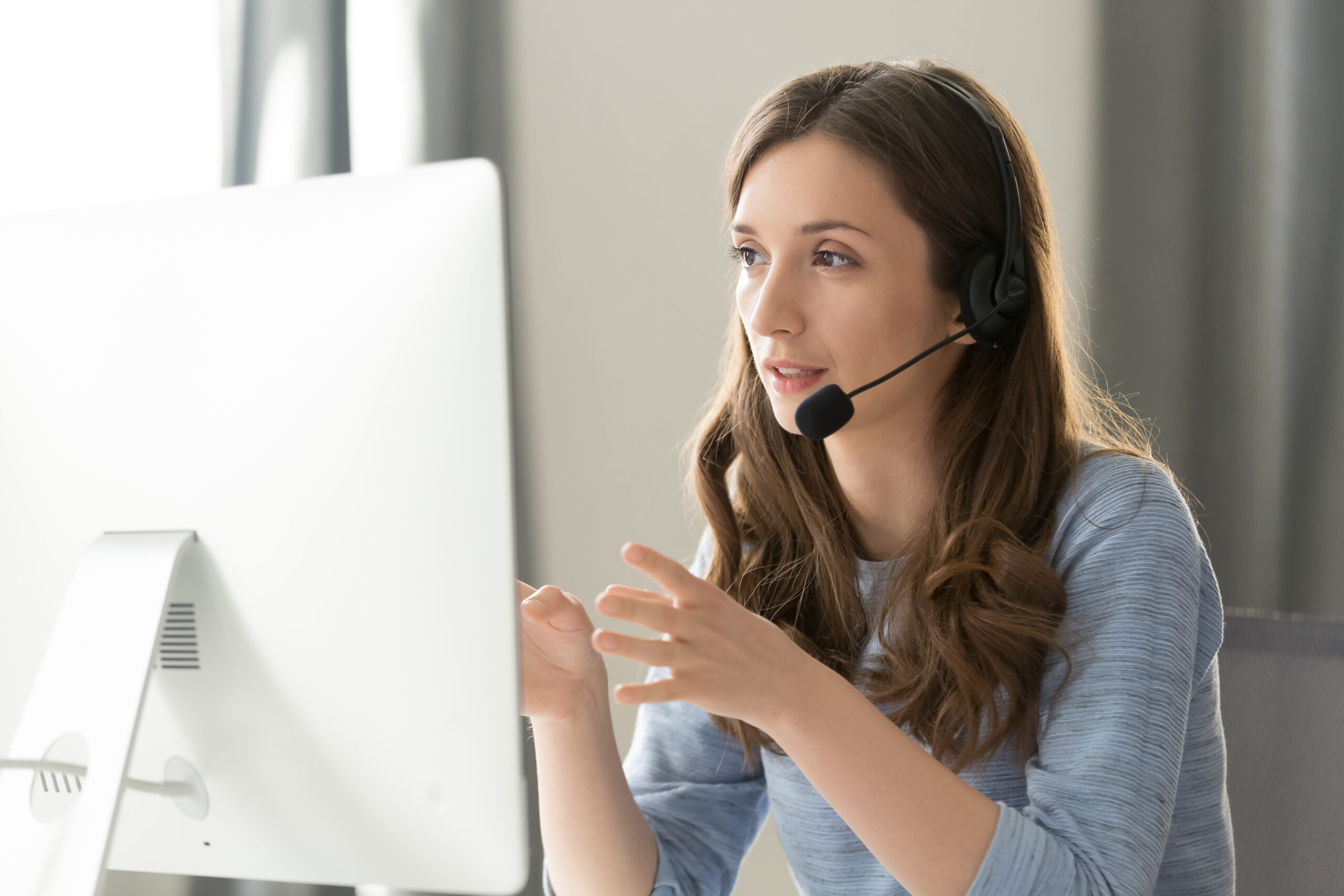 Coronis Health Woman with headset having a virtual call at desktop computer