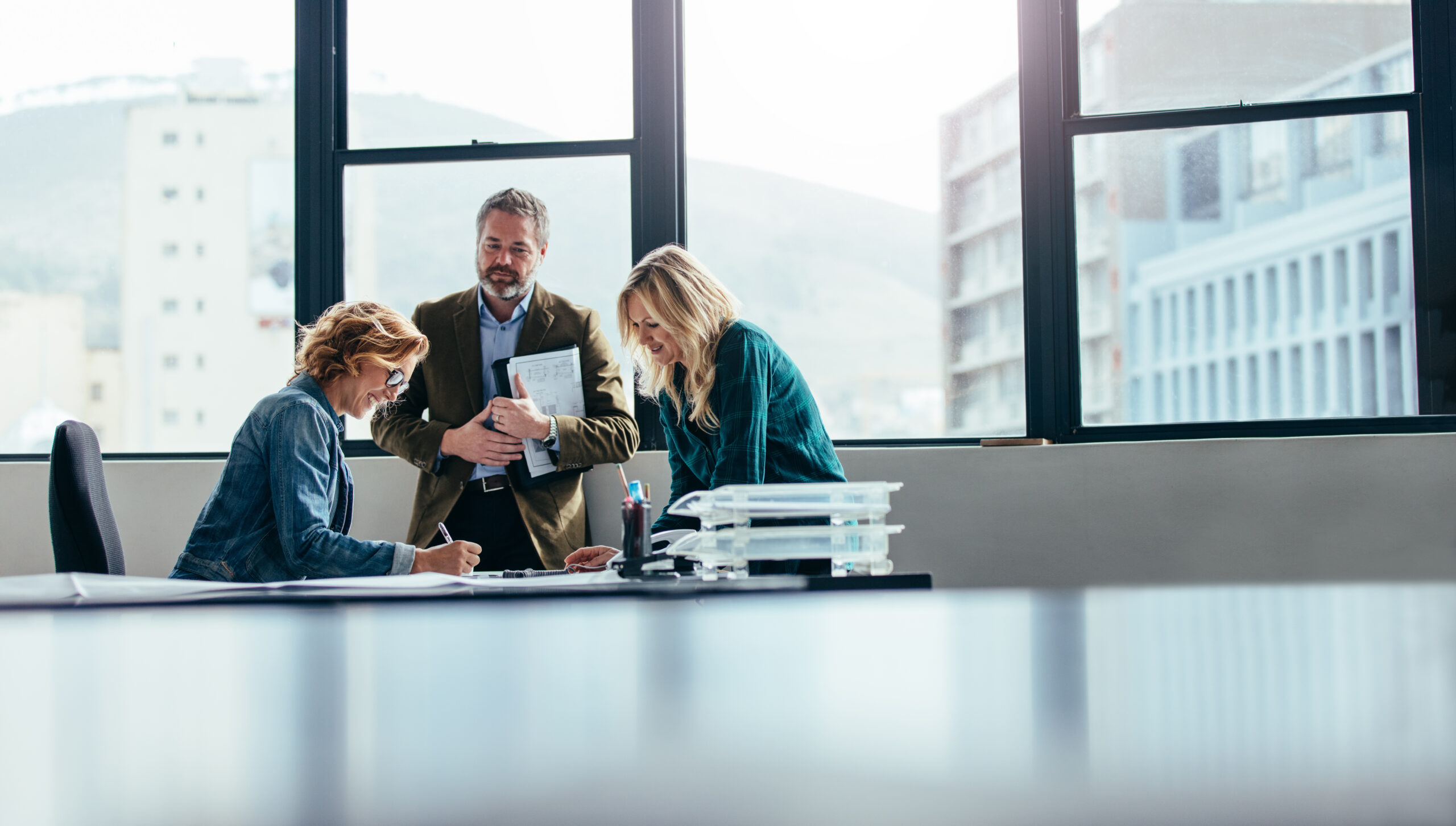 three workers collaborating on a project in an office setting coronis health