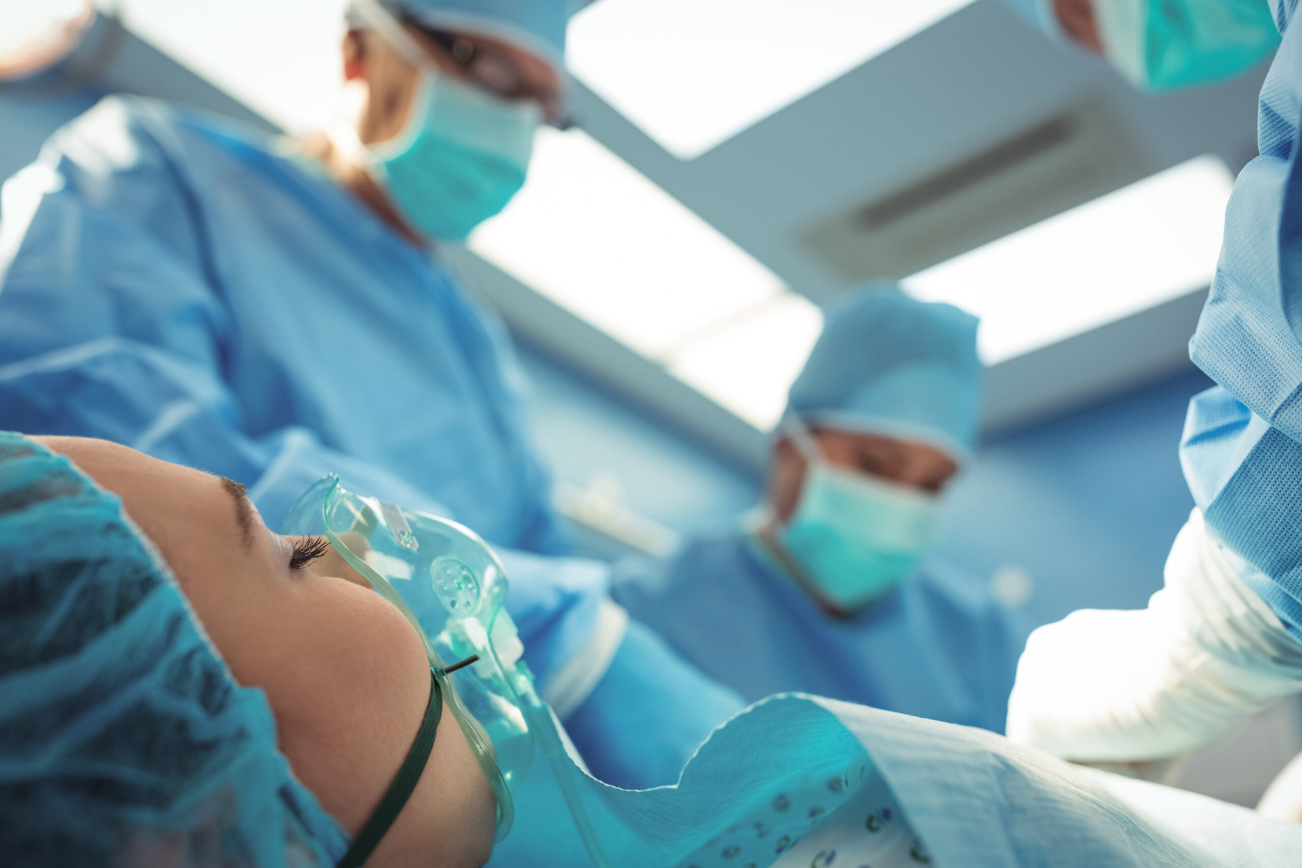 coronis health patient with oxygen mask in room with surgeons