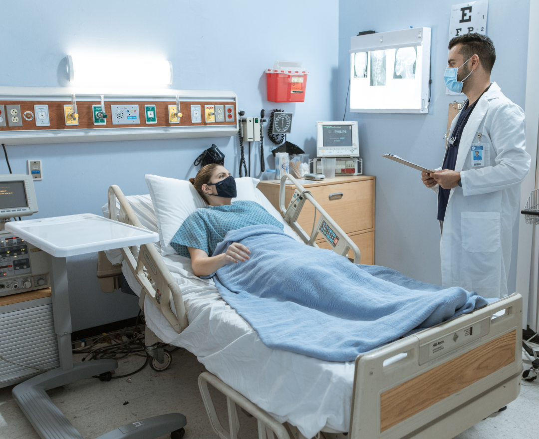 coronis health hospital worker talking with patient in hospital bed